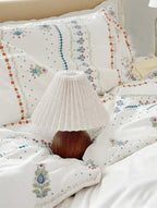 Floral embroidered bedding with a lamp on a bed