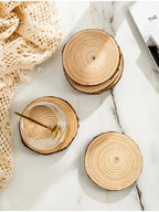 Wooden coasters on a marble surface with a glass of water and a gold straw.