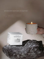 Candle with packaging on a stone surface with a neutral background