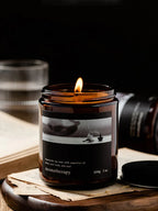 Candle in an amber jar with a label on a wooden surface