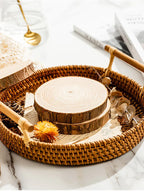 Wooden slices and decorative items on a woven tray with a marble background