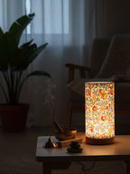 Decorative lamp with floral pattern on a table in a dimly lit room.