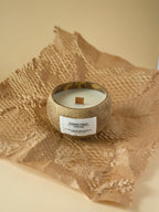 Candle in a coconut shell on burlap fabric with a beige background