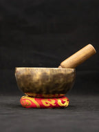 Tibetan singing bowl with wooden striker on a black background