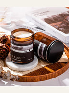 Aromatherapy candle in an amber jar on a wooden tray with books and dried flowers.