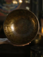 Hand holding a dark wooden bowl against a blurred background