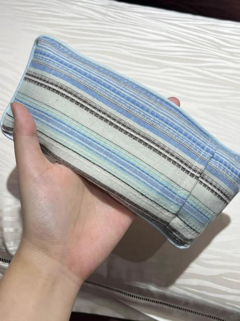 Hand holding a striped fabric item on a textured surface