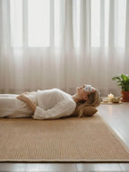 Woman lying on a mat with a headband, in a bright room with large windows.